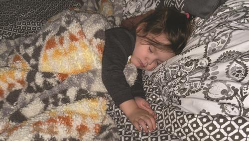 A young child sleeping on their side covered in soft blankets. Photo by John Hawley.